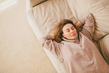 Young woman relaxing on couch in a cozy house.