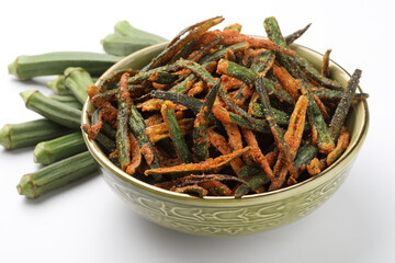 Bhindi kurkure or crunchy okra or ladies' fingers, a Rajasthani traditional dish served in a ceramic bowl on wooden board along with ingredient for the recipe