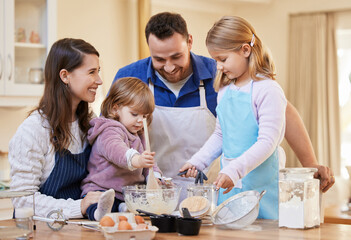 Family time is all that matters. Shot of a family baking together while a little girl stirs a bowl of cake batter.