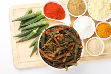 Fototapeta na wymiar Bhindi kurkure or crunchy okra or ladies' fingers, a Rajasthani traditional dish served in a ceramic bowl on wooden board along with ingredient for the recipe