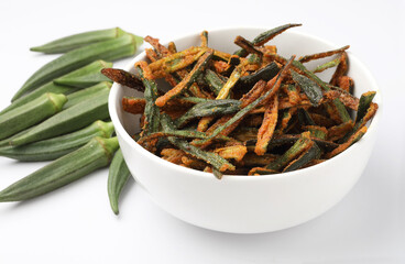 Bhindi kurkure or crunchy okra or ladies' fingers, a Rajasthani traditional dish served in a ceramic bowl on wooden board along with ingredient for the recipe