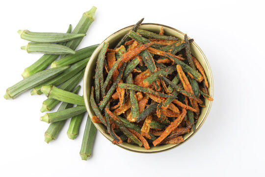 Bhindi kurkure or crunchy okra or ladies' fingers, a Rajasthani traditional dish served in a ceramic bowl on wooden board along with ingredient for the recipe