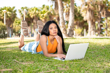 Portrait of an African American woman using the computer next to some palm trees on a sunny day