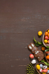 Easter hunt concept background with chocolate eggs and bunny on wooden table copy space. View from above