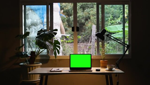 Home office with laptop mockup green screen for playlist music and aroma coffee, document book on table decor as a lamp and monstera tree pot plants house modern loft interior decorations workspace.4K