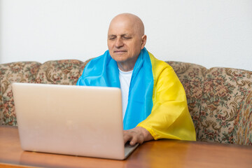 elderly man with laptop and ukraine flag