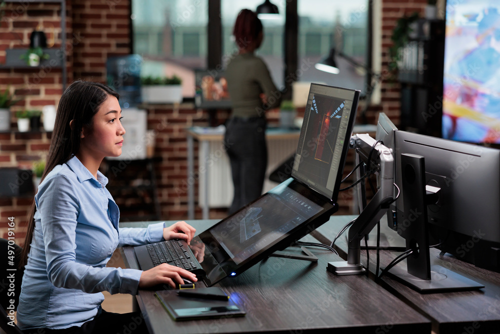 Poster confident asian 3d model creator sitting at desk with multiple monitors while working on cgi. digita