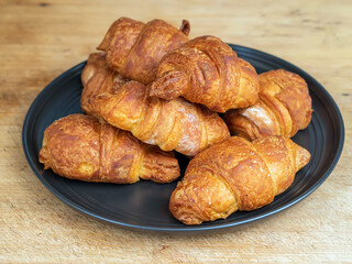 Homemade croissants on a black plate.
