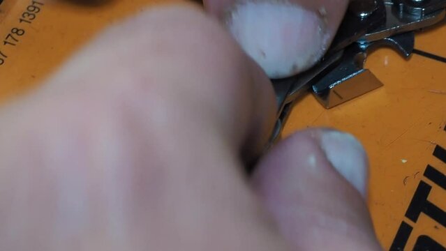 Man places the chain saw link of a chainsaw for riveting on a workbench. Close-up shot with selective focus