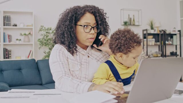 Young black mother working from home and taking care of baby, extra income