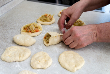 hands of a female cook put the stuffing in the pies.
