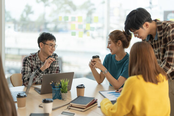 Fototapeta premium Group of asian business discussing project on laptop colleague, working together in pairs at shared workplace, analyzing electronic documents.