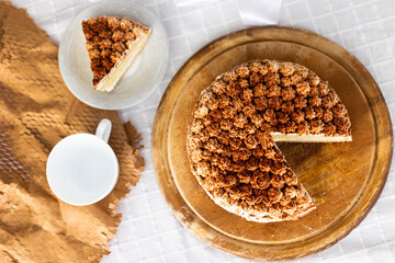 Homemade tiramisu cake with cocoa on top on wooden platter on white tablecloth