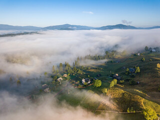 Mountain settlement in the Ukrainian Carpathians in the morning mist. Aerial drone view.