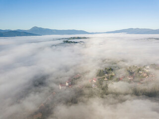 Mountain settlement in the Ukrainian Carpathians in the morning mist. Aerial drone view.