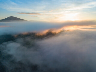 Naklejka premium The rays of dawn over the fog in the Ukrainian Carpathians. Aerial drone view.