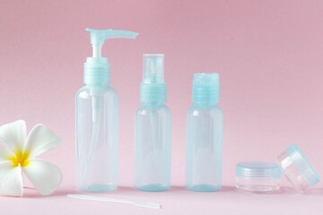 Travel cosmetics on a pink background. Set of small empty bottles for cosmetics, side view.