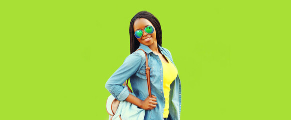 Portrait of happy smiling young african woman posing with backpack on green background, banner blank copy space for advertising text