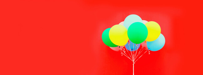 Bundle of colorful balloons on red background, blank copy space for advertising text