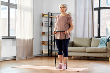 sport, fitness and healthy lifestyle concept - smiling senior woman exercising with resistance band...