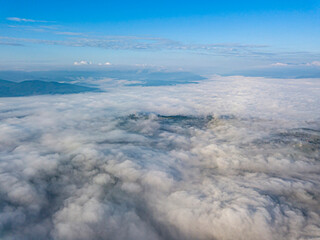 High flight above the clouds in the mountains. Aerial drone view.