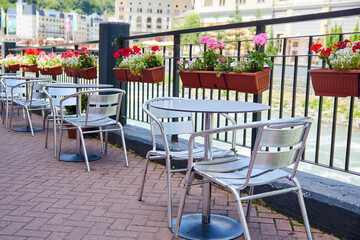 Fototapeta na wymiar Summer cafe tables with flowers near the river