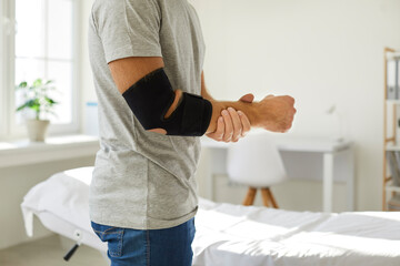 Bandage on elbow of unknown man that he wears to restore and relieve joint pain. Cropped image side...