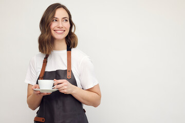Beautiful young barista woman smiling and serving a cup of coffee. Isolated on white background looking professional. - obrazy, fototapety, plakaty