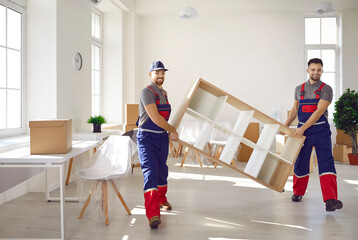 Truck delivery service workers in workwear uniforms removing furniture from house or apartment. Two...