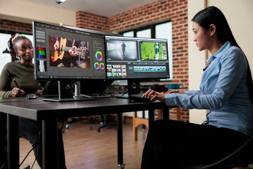 Videography expert in post production house editing footage frames and improving visual quality using specialized software. Video editor in creative agency room sitting at multi monitor workstation.