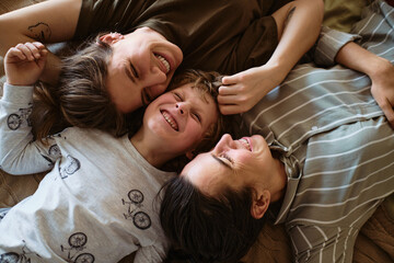 High angle view of happy lesbian family with little son relaxing on bed together