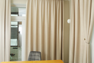 beige curtain folds and white tulle close up photo on window background