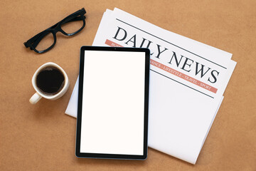 daily newspaper and white mock up screen tablet with coffee cup on wooden table