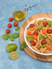 pasta with meat and vegetables in a white plate and a wooden board.