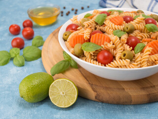 pasta with meat and vegetables in a white plate and a wooden board.