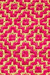 Knitted texture close up. Texture of mosaic fabric with yellow pink geometric ethnic pattern. Crochet mosaic pattern. Rhombus and square pattern.