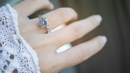 Close up of an elegant diamond ring on woman finger with window and sunlight background. love and...