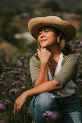 Thai woman is sitting on a stump in flower field