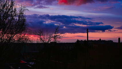 Panorama of colorful sunset in the city. Golden red, purple clouds on the background of buildings. Beauty in nature. Scenic landscape.