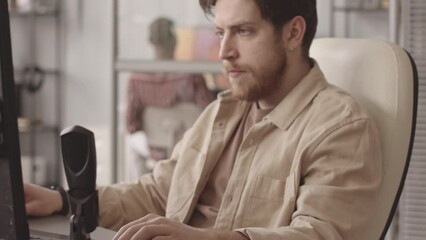 Waist up slowmo of serious video game developer making new game on PC while his African American colleague testing it in background, working together in modern office