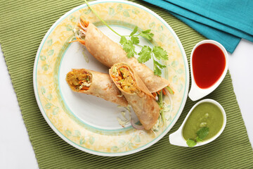 Indian Frankie Veg chapati Wrap / Kathi Roll, served in a plate with sauce & mint chutney. selective focus