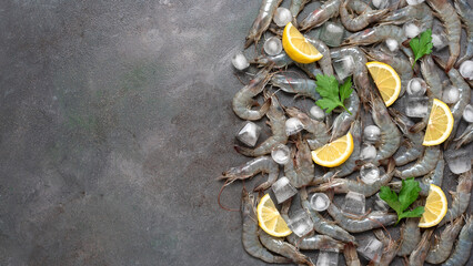 Raw tiger prawns with ice and lemon on a dark grunge background. Top view, flat lay. Fresh shrimp....