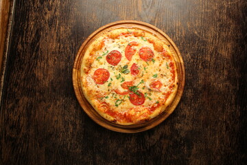 Pizza with tomatos, cheese and ham on a dark background. Italian pizza
