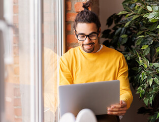 Cheerful black freelancer using laptop