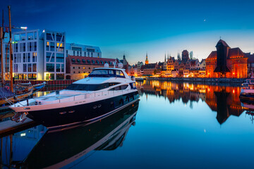 Obraz premium Historic port crane in Gdansk reflected in the Motlawa river at dusk, Poland