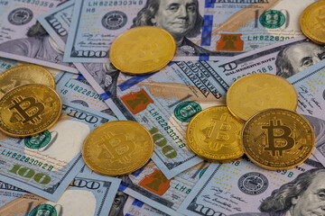 yellow bitcoin coins scattered over US dollar paper banknotes, closeup with selective focus