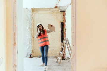 architect woman in construction site talking on mobile phone and blueprints.Home renovation
