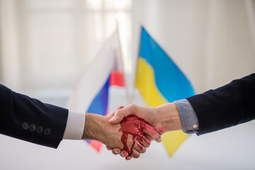 Representatives of Ukraine and Russia shaking hands, blood hand concept.
