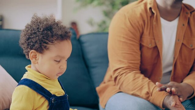 Happy child looking around while father sitting on sofa and watching tv