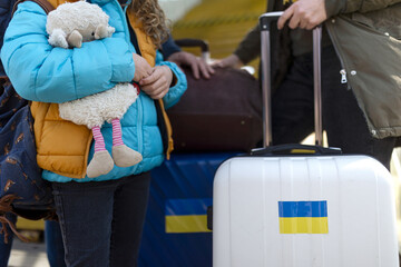 Close-up of Ukrainian immigrants with luggage waiting at train station, Ukrainian war concept.